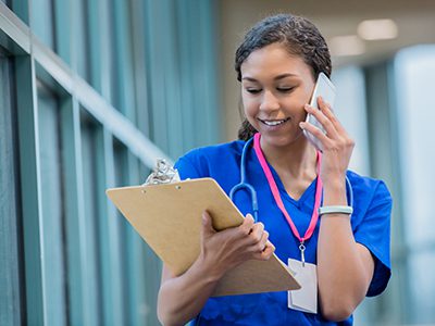 Nurse making phone call in hospital while studying patient chart