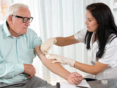 Nurse with syringe is taking blood for test at the doctor office