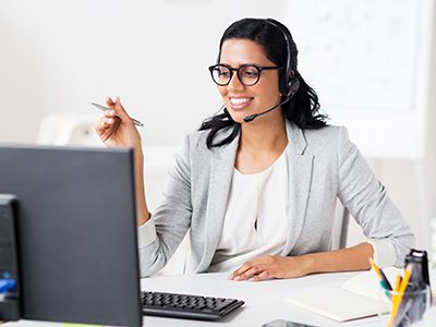 communication, business, people and technology concept - smiling businesswoman or helpline operator with headset and computer at office